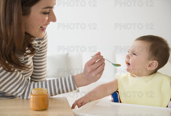 Mother feeding baby in high chair