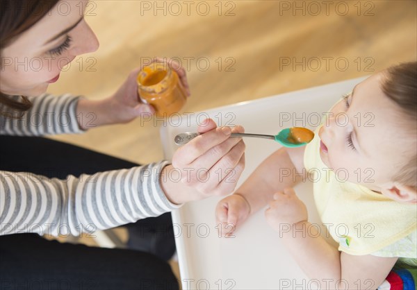 Mother feeding baby in high chair