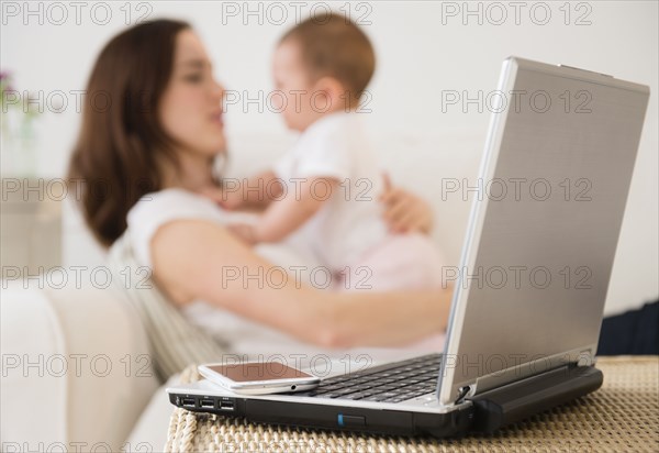 Laptop and cell phone beside mother with baby