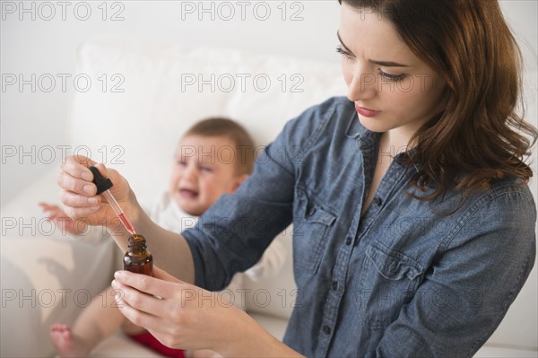 Mother giving crying baby medicine