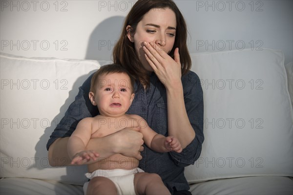 Tired mother holding crying baby