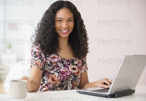 Mixed race woman using laptop at table