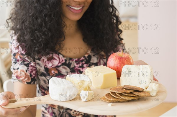 Mixed race woman carrying fruit and cheese board