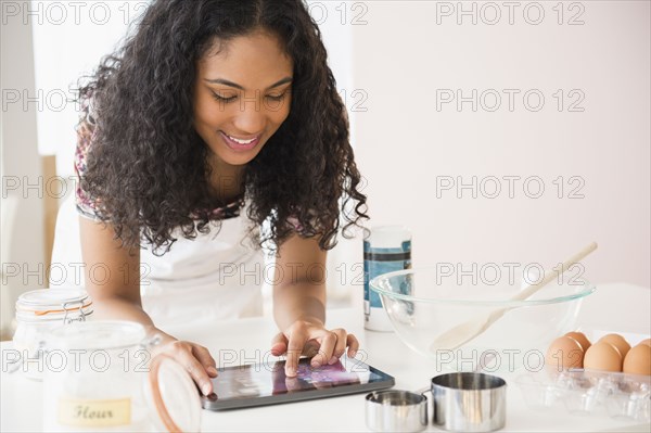 Mixed race woman using digital tablet while cooking