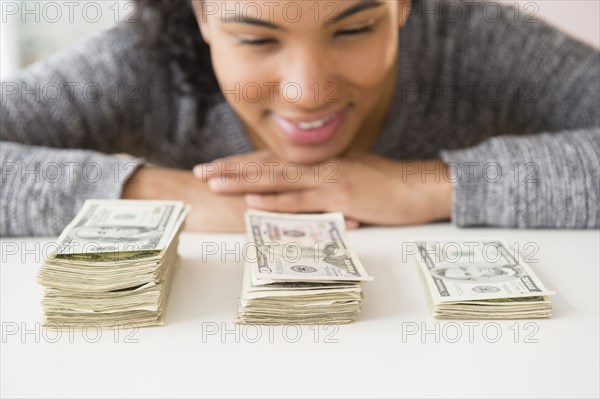 Mixed race woman counting stacks of money