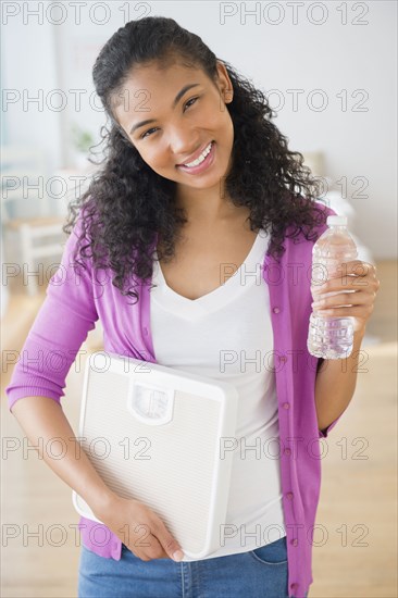 Mixed race woman with scale and bottle of water