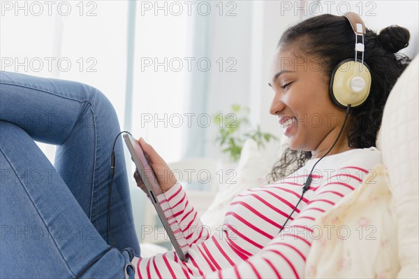 Mixed race woman listening to headphones on bed