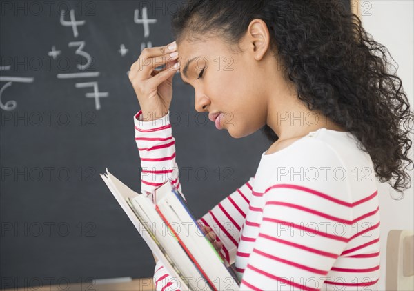 Frustrated mixed race teacher rubbing her forehead