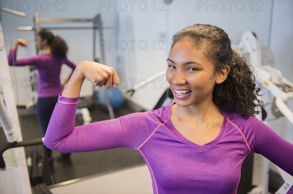 Mixed race woman flexing muscles in gym