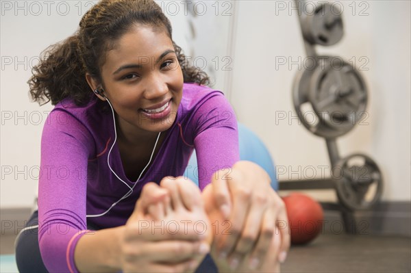 Mixed race woman stretching in gym