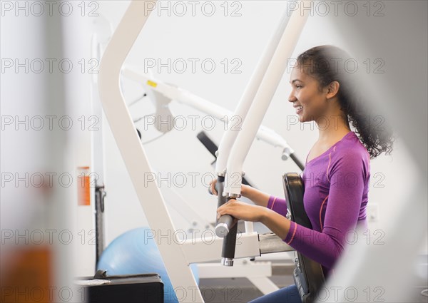 Mixed race woman using exercise machine in gym