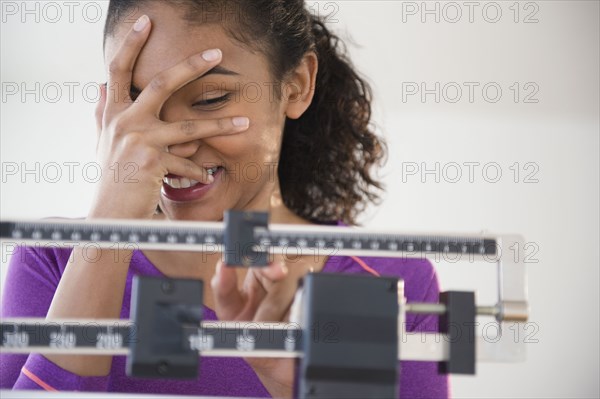 Mixed race woman grimacing at scale