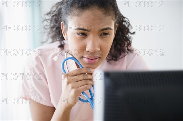 Mixed race nurse using computer in hospital