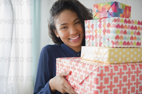 Mixed race woman carrying stack of gifts