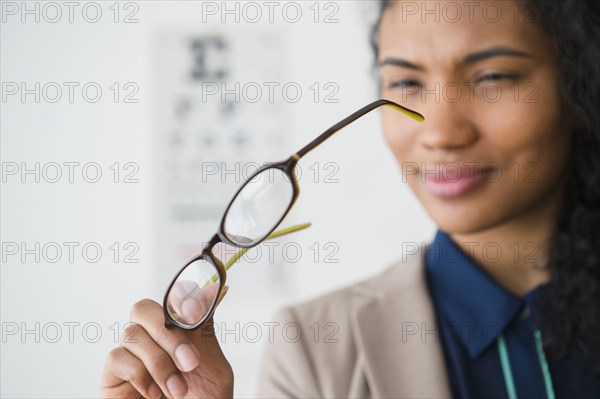 Mixed race woman examining eyeglasses