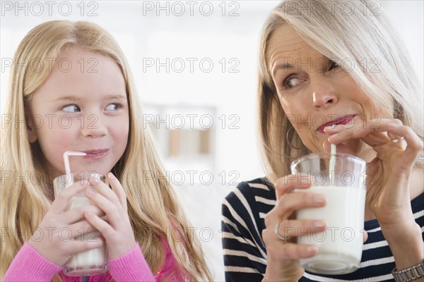 Senior Caucasian woman and granddaughter drinking milk