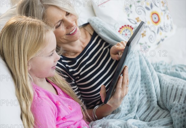 Senior Caucasian woman and granddaughter using digital tablet on sofa