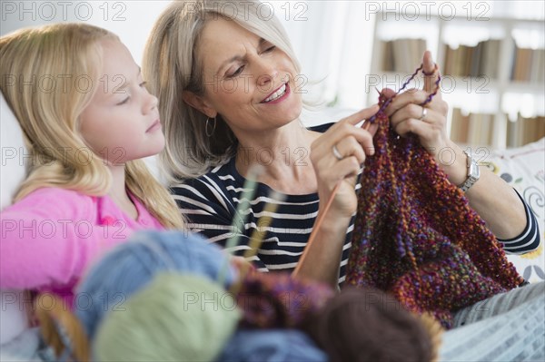 Senior Caucasian woman and granddaughter knitting on sofa