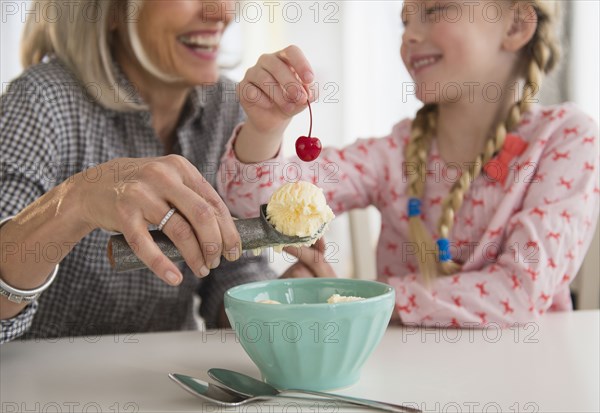 Senior Caucasian woman and granddaughter making ice cream sundae