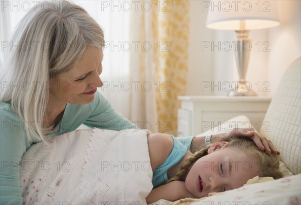 Senior Caucasian woman putting granddaughter to bed