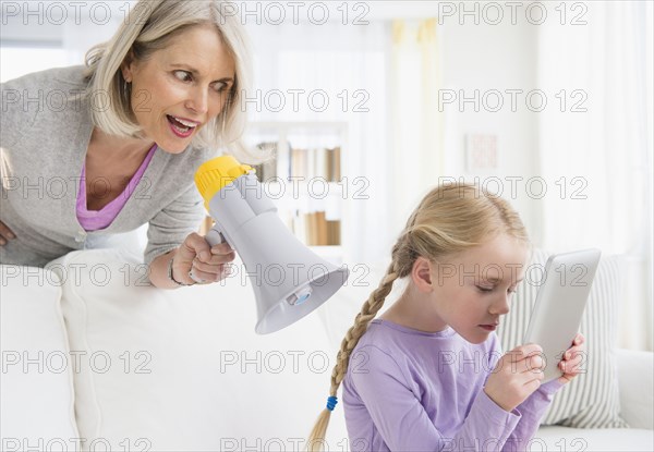 Senior Caucasian woman yelling in megaphone at granddaughter