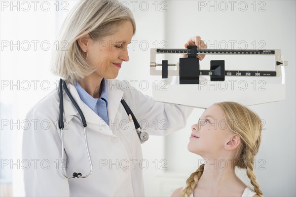 Caucasian doctor weighing patient
