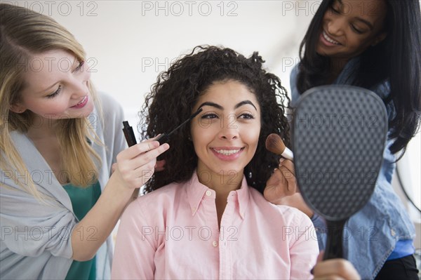 Women doing friend's makeup in mirror