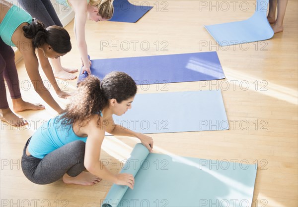 Women rolling up mats in yoga class