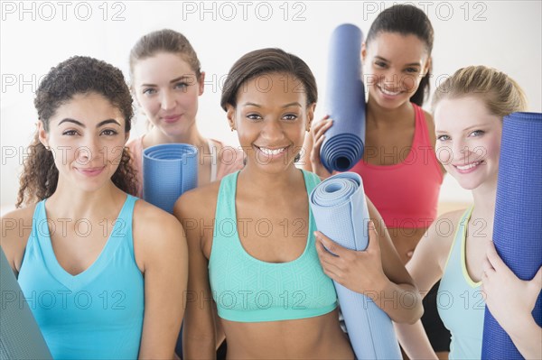 Women smiling together with exercise mats