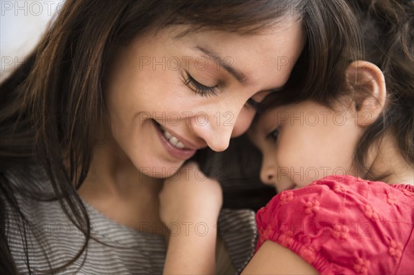 Hispanic girl whispering in mother's ear