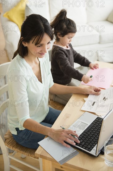 Hispanic mother and daughter working at table