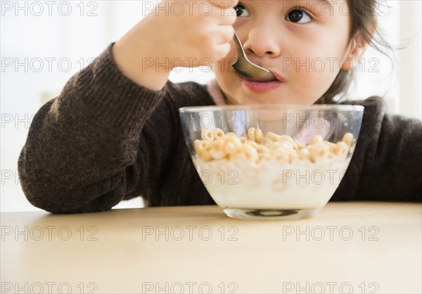 Hispanic girl eating bowl of cereal