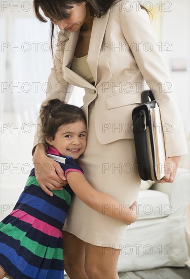 Hispanic daughter hugging mother as she leaves for work