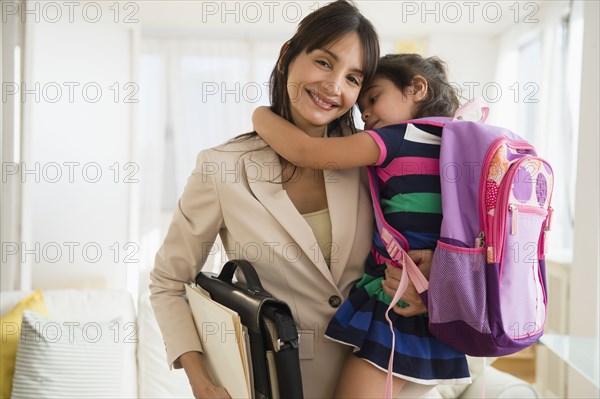 Hispanic daughter hugging mother as she leaves for work