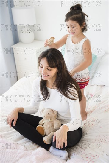 Hispanic girl brushing mother's hair