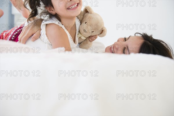 Hispanic mother and daughter relaxing on bed