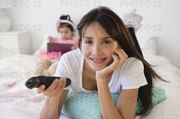 Hispanic mother and daughter relaxing on bed
