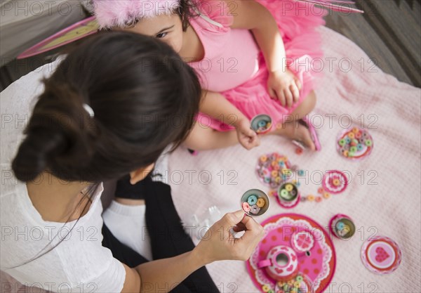 Hispanic mother and daughter having tea party