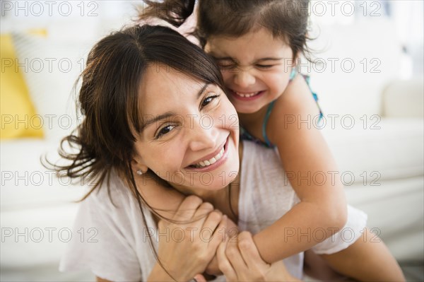 Hispanic mother and daughter playing in living room