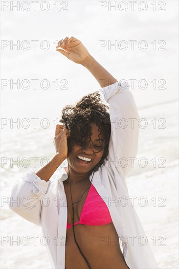 African American woman listening to headphones on beach