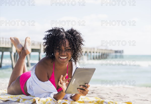 African American woman using digital tablet on beach