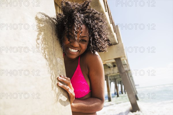 African American woman under wooden pier on beach