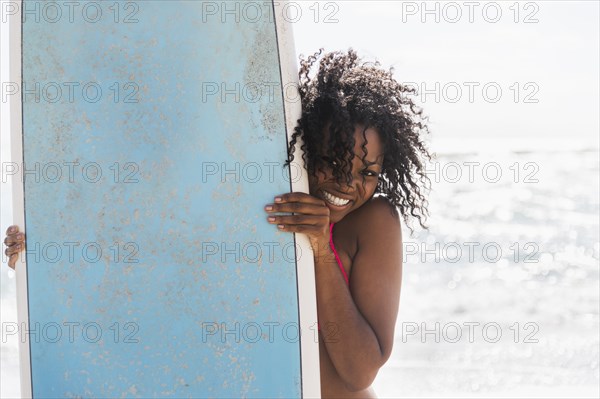 African American woman holding surfboard on beach