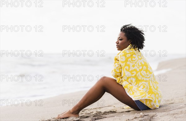 African American woman wrapped in towel on beach
