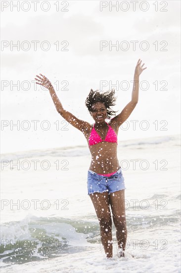 African American woman playing in waves on beach