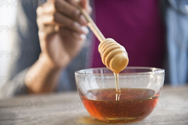 Mixed race woman holding honey dipper