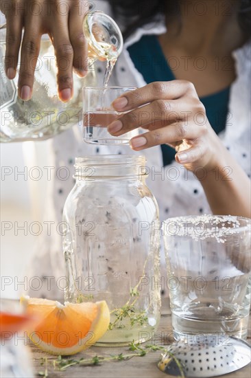 Mixed race woman making cocktail