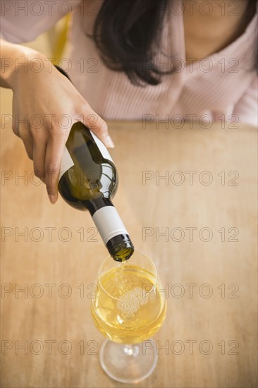 Mixed race woman pouring glass of wine