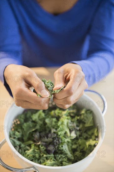 Mixed race woman washing kale