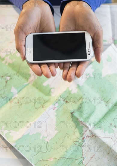 Mixed race woman holding cell phone over map